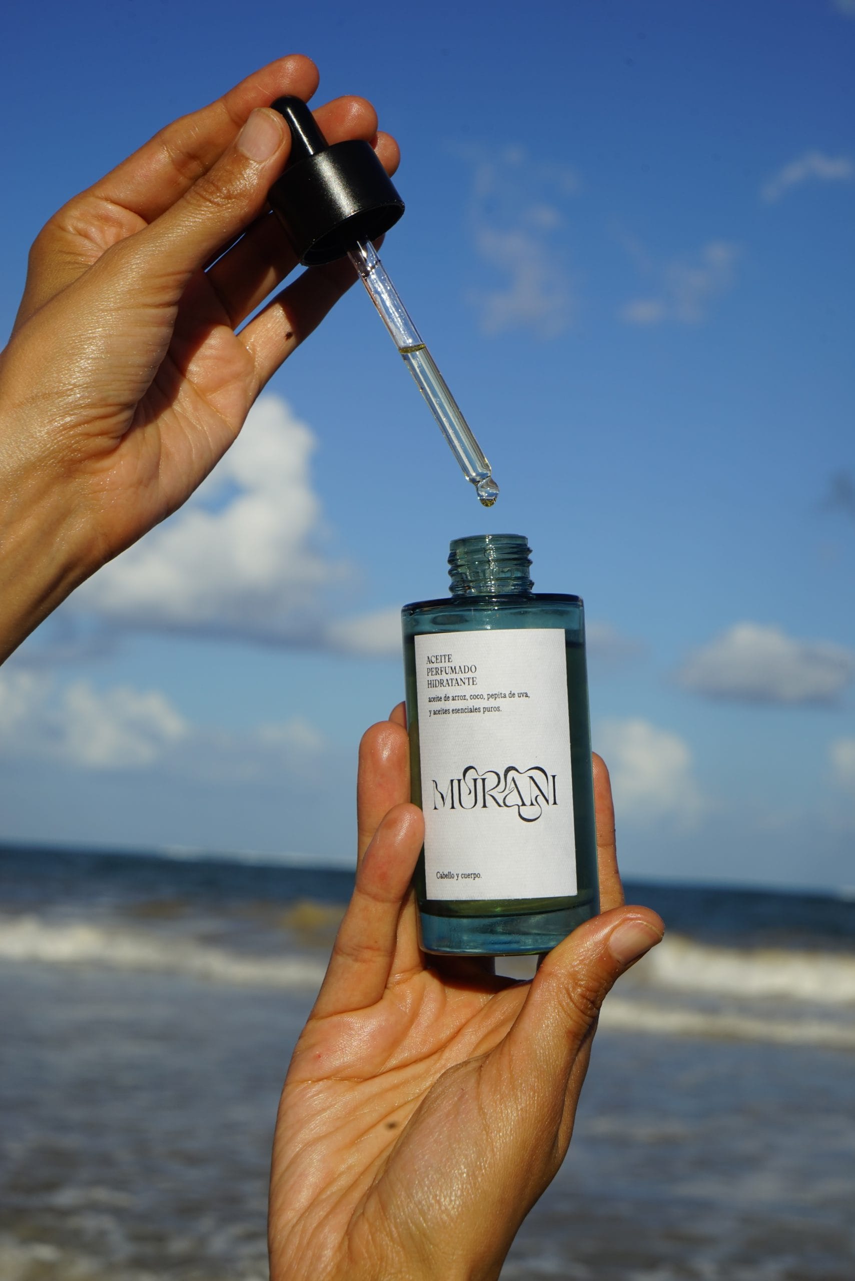 Aceite botánico Mukani sostenido frente al cielo